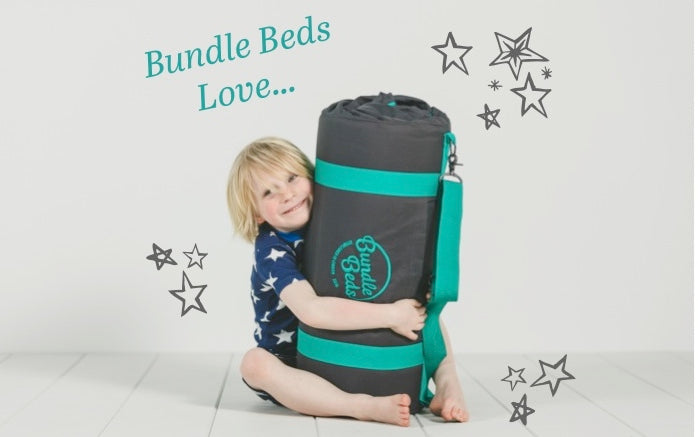 Young boy cuddles his cosy roll out sleepover Bundle Bed.